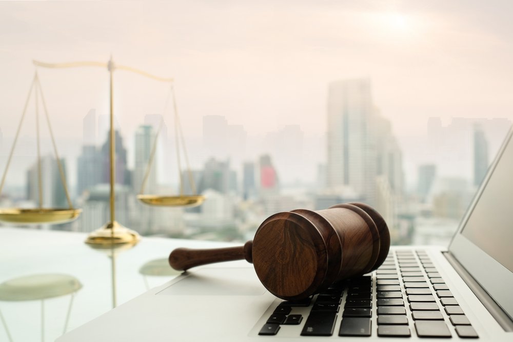 a Gavel and Scales of Justice on a Desk with a Cityscape in the Background, Symbolizing Law and Legal Matters in an Urban Setting, with a Focus on Navigating Cyber Law.