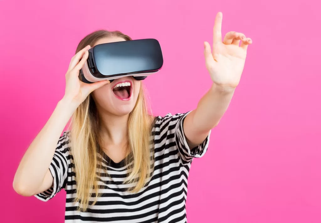 a Woman Wearing an Ar Headset Excitedly Gestures with Her Hand Against a Bright Pink Background. Vr and Ar