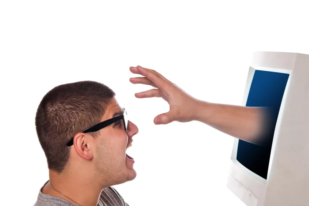 Man with Glasses Shouting in Surprise at a Hand Reaching out from a Computer Screen, Isolated on a White Background, Symbolizing Cyber Threats.