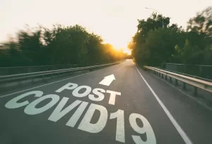 Empty Road at Dusk with "post-pandemic World" Text and an Arrow Symbol Painted on the Pavement, Conveying the Concept of Moving Forward After the Pandemic.