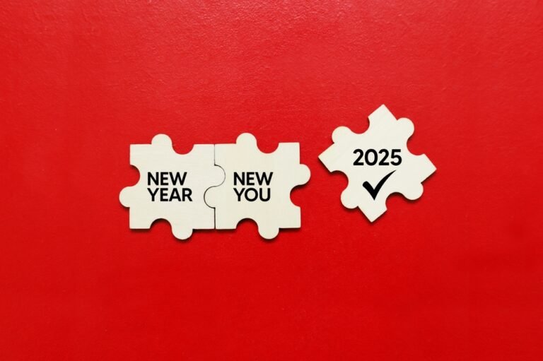 Three wooden puzzle pieces rest on a vibrant red background, displaying the words "New Year," "New You in 2025," and "2025" with a check mark.