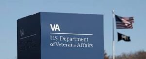 a Sign for the U.s. Department of Veterans Affairs Stands Tall Under a Clear Sky, with Two Flags Waving Proudly in the Background, Marking a New Era of Shared Accountability.