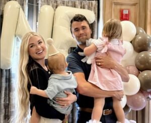 a Smiling Man and Woman Hold Two Young Children in Front of Large White Balloons and Pastel Balloon Decorations Indoors, Capturing a Joyful Moment in America.